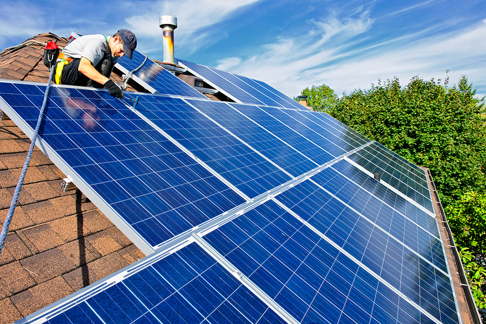 En man installerar solceller på ett hustak